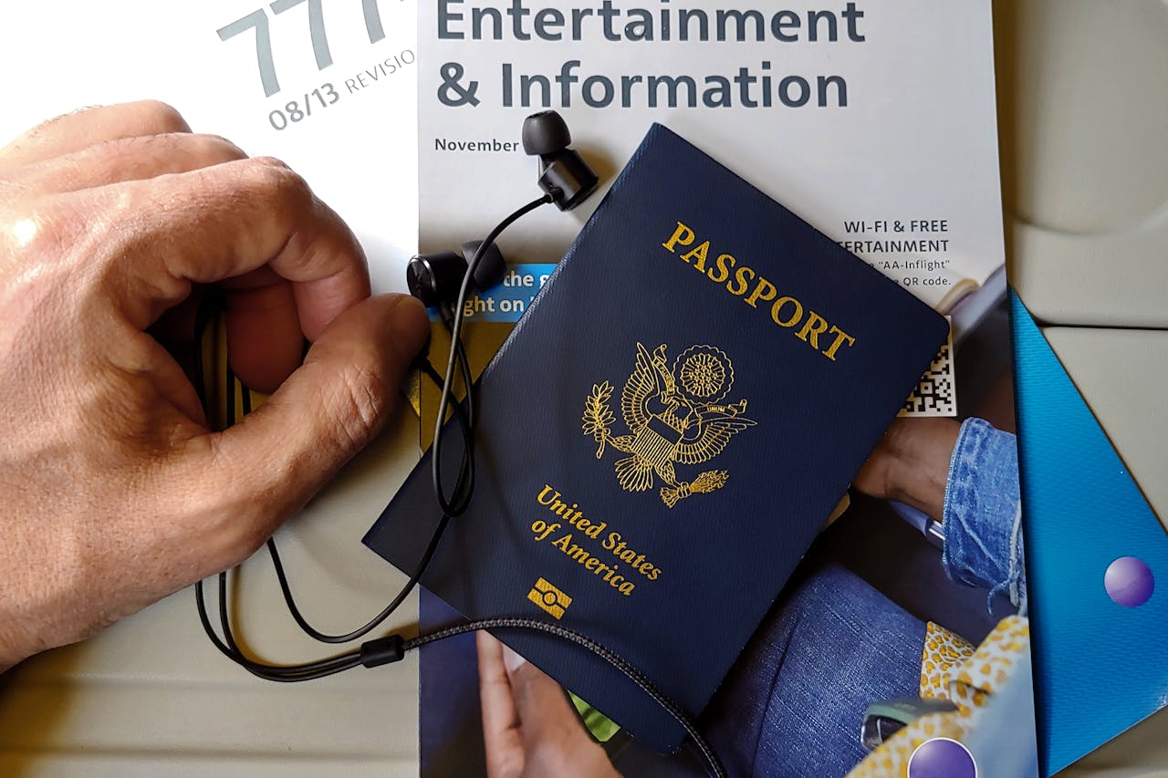 Close-up of US passport with inflight magazine and headphones on an airplane seat, ready for travel.